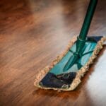 A detailed view of a mop cleaning a wooden floor, showing texture and pattern.